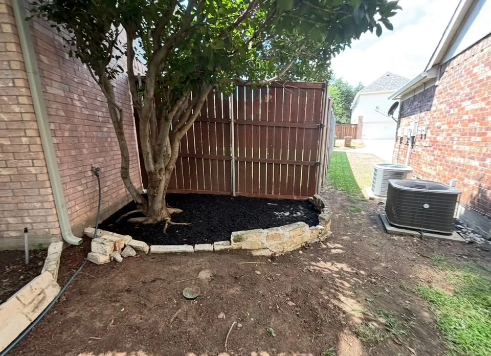 Completed tree bed with fresh black mulch and stone edging
