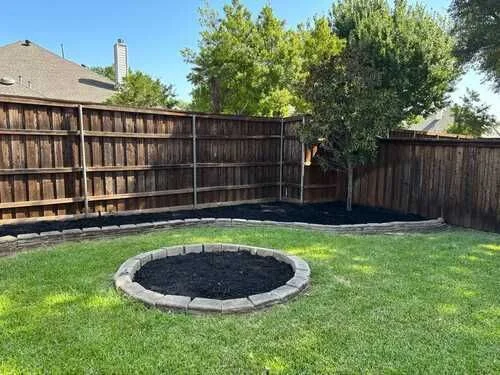 Wood privacy fence behind a lawn and fresh garden bed