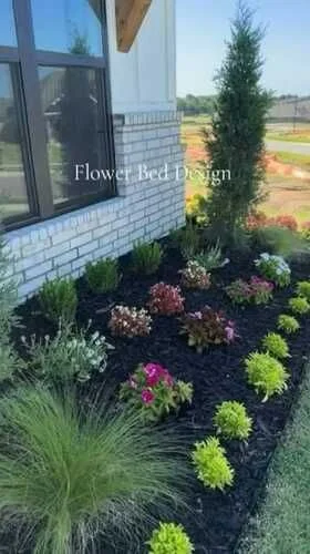 Newly designed flower bed with fresh dark mulch and colorful plantings