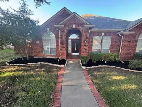 Brick home with a maintained front lawn and landscape beds