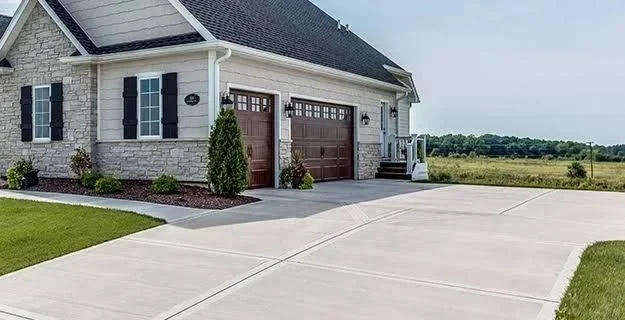 Clean concrete driveway in front of a stone home